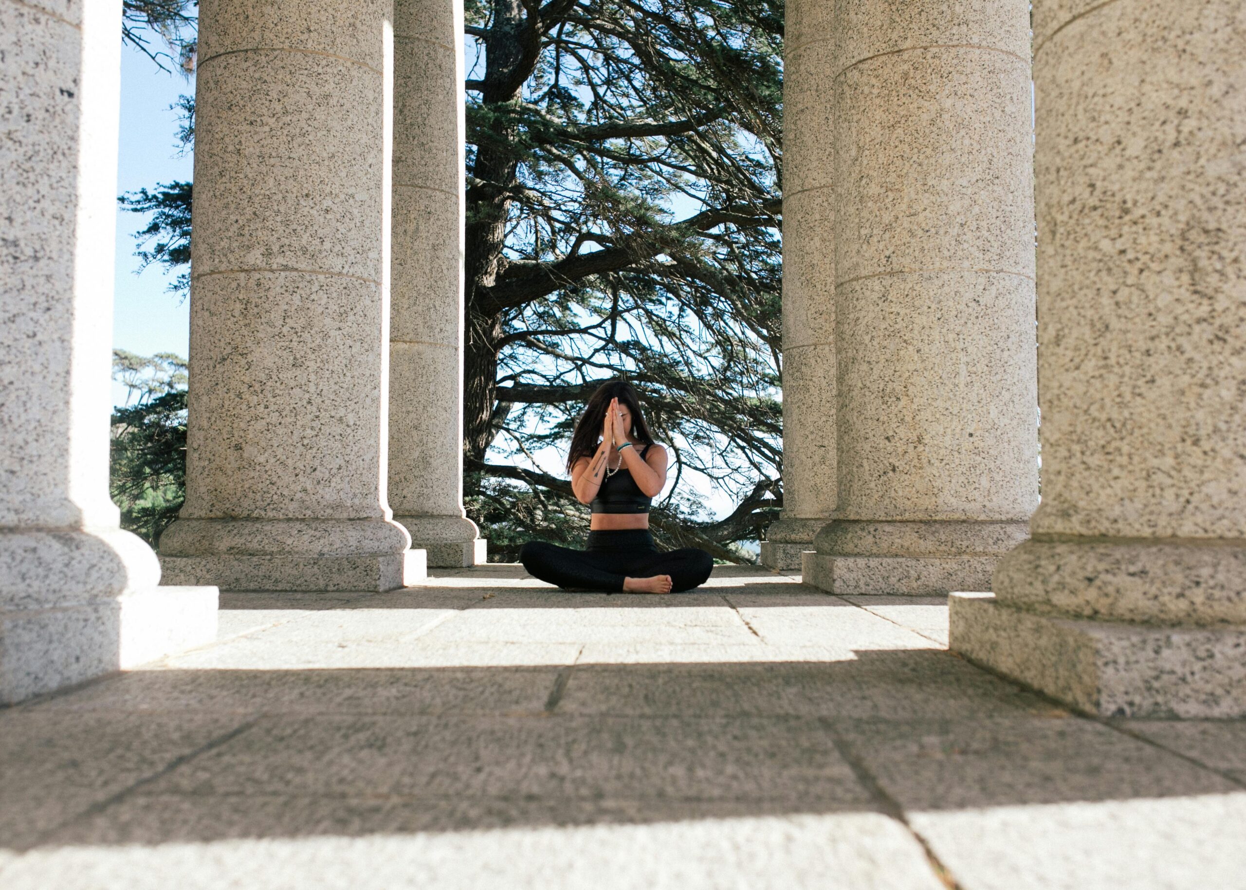 Woman practicing yoga meditation outdoors among stone columns, embracing tranquility.
