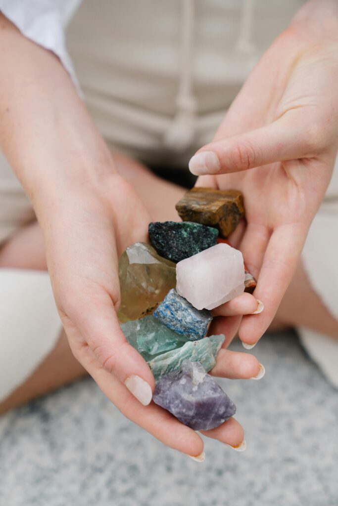 Close-up of hands gently holding a collection of raw mineral stones in various colors and textures.